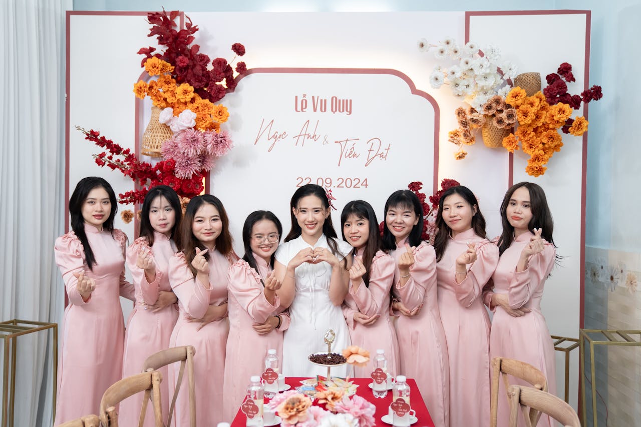 A group of bridesmaids in pink dresses posing elegantly in a decorated indoor setting.