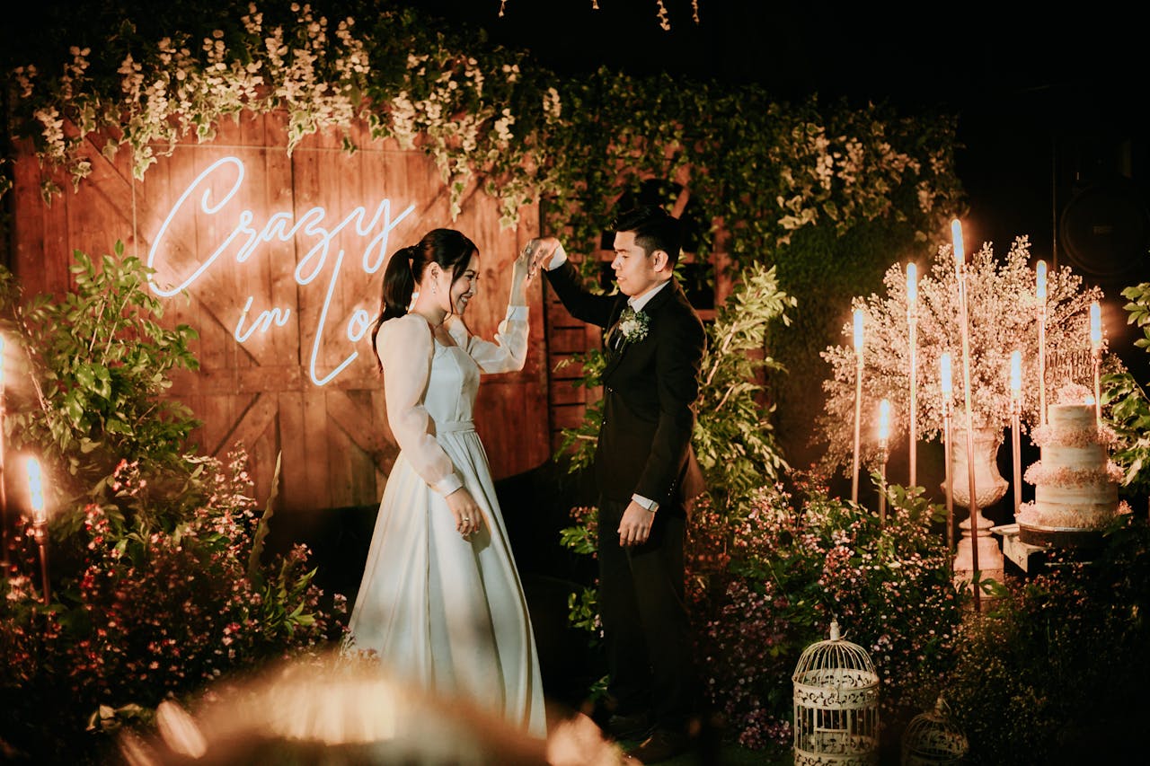 Bride and groom dancing at an intimate wedding ceremony with romantic neon lights and floral decor.